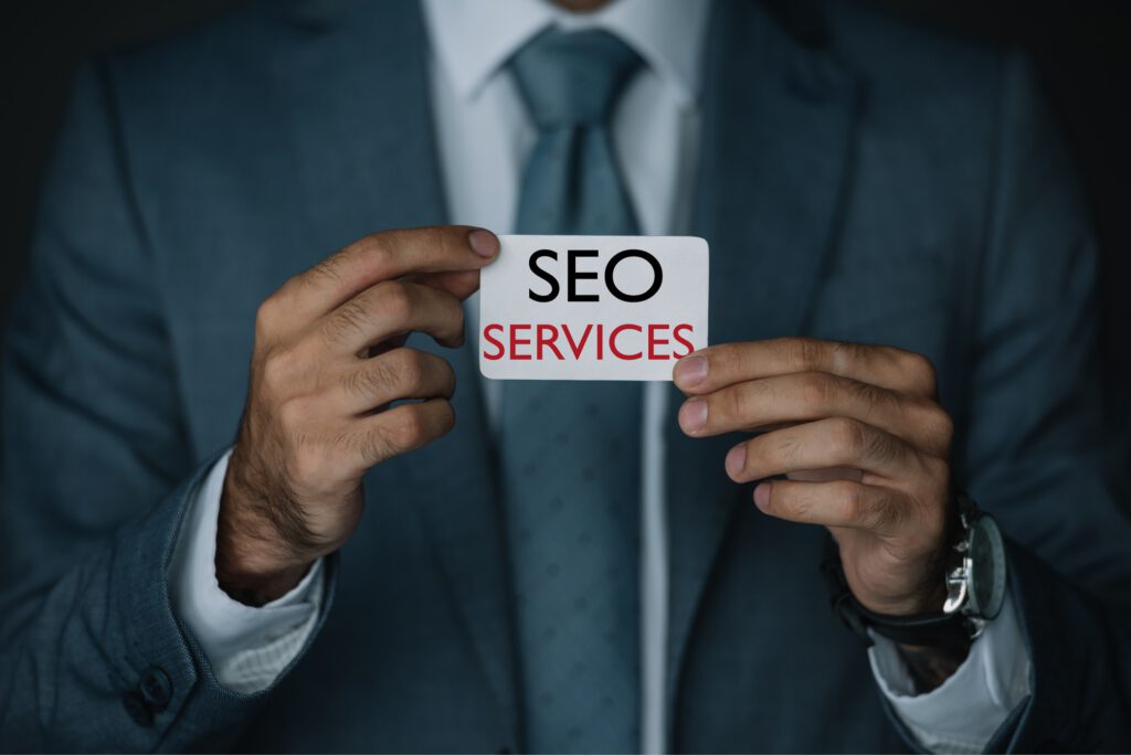 cropped view of developer in suit holding business card with SEO services